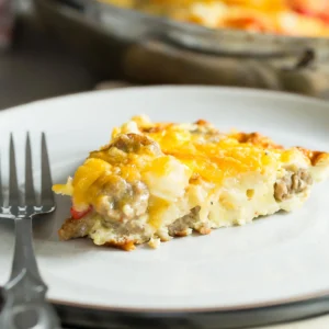 Slice of a chicken sausage and potato frittata on a white plate with a fork