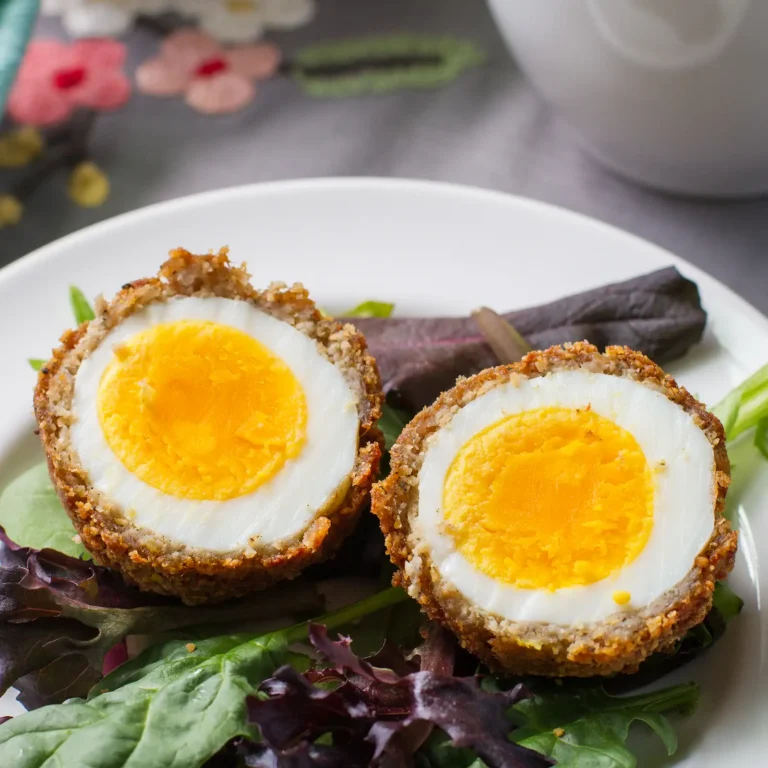 11:56 AMClaude responded: Two halved Jones breakfast scotch eggs showing a jammy soft-boiled yolk surrounded by a layer of pork sausage and golden almond flour crust, served on a bed of…Two halved Jones breakfast scotch eggs showing a jammy soft-boiled yolk surrounded by a layer of pork sausage and golden almond flour crust, served on a bed of mixed greens.