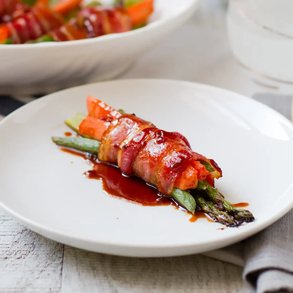 11:19 AMClaude responded: A single Jones bacon-wrapped bundle of asparagus, carrots, and green beans glazed with soy honey sauce, plated on a white dish with a serving bowl of additiona…A single Jones bacon-wrapped bundle of asparagus, carrots, and green beans glazed with soy honey sauce, plated on a white dish with a serving bowl of additional bundles in the background.