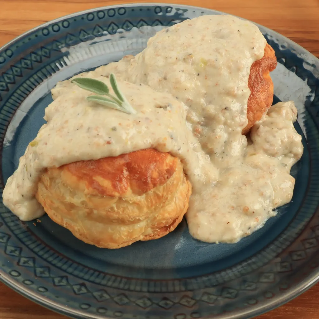 10:51 AMClaude responded: Two golden flaky biscuits smothered in creamy Jones Scrapple gravy, garnished with a fresh sage sprig, served on a blue ceramic plate.Two golden flaky biscuits smothered in creamy Jones Scrapple gravy, garnished with a fresh sage sprig, served on a blue ceramic plate.