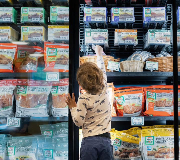 Little boy reaching in store freezer