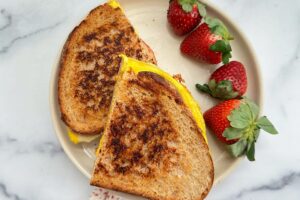 Toasted breakfast sandwich with Canadian bacon and strawberries on the side, canadian bacon breakfast