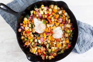 Skillet hash with eggs, bacon, sweet potato, bell peppers, and zucchini.