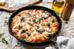 Jones Dairy Farm sausage and mozzarella skillet pizza topped with fresh oregano in a cast iron pan