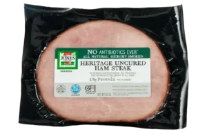 Jones Dairy Farm No Antibiotics Ever Heritage Uncured Ham Steak, 6.5 oz, all natural hickory smoked, Certified Gluten Free with no sugar, no nitrates or nitrites added, and 19g protein per 3 oz serving, in vacuum-sealed black packaging.