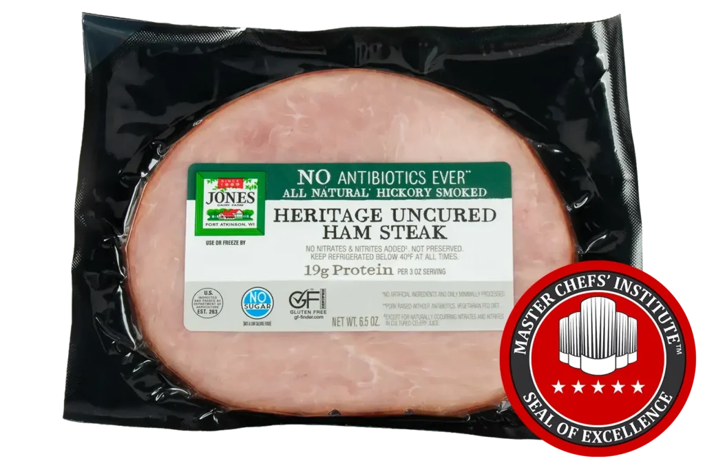 Jones Dairy Farm No Antibiotics Ever Heritage Uncured Ham Steak, 6.5 oz, all natural hickory smoked, Certified Gluten Free with no sugar, no nitrates or nitrites added, and 19g protein per 3 oz serving, in vacuum-sealed black packaging, with MCI Master Chefs' Institute Seal of Excellence.