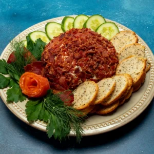 Bacon and lox cheeseball coated in crispy Jones bacon, served on a platter with smoked salmon, sliced cucumbers, poppy seed crackers, fresh dill, and parsley