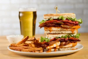 Buffalo chicken club sandwich with bacon, lettuce, and tomato, served with sweet potato fries