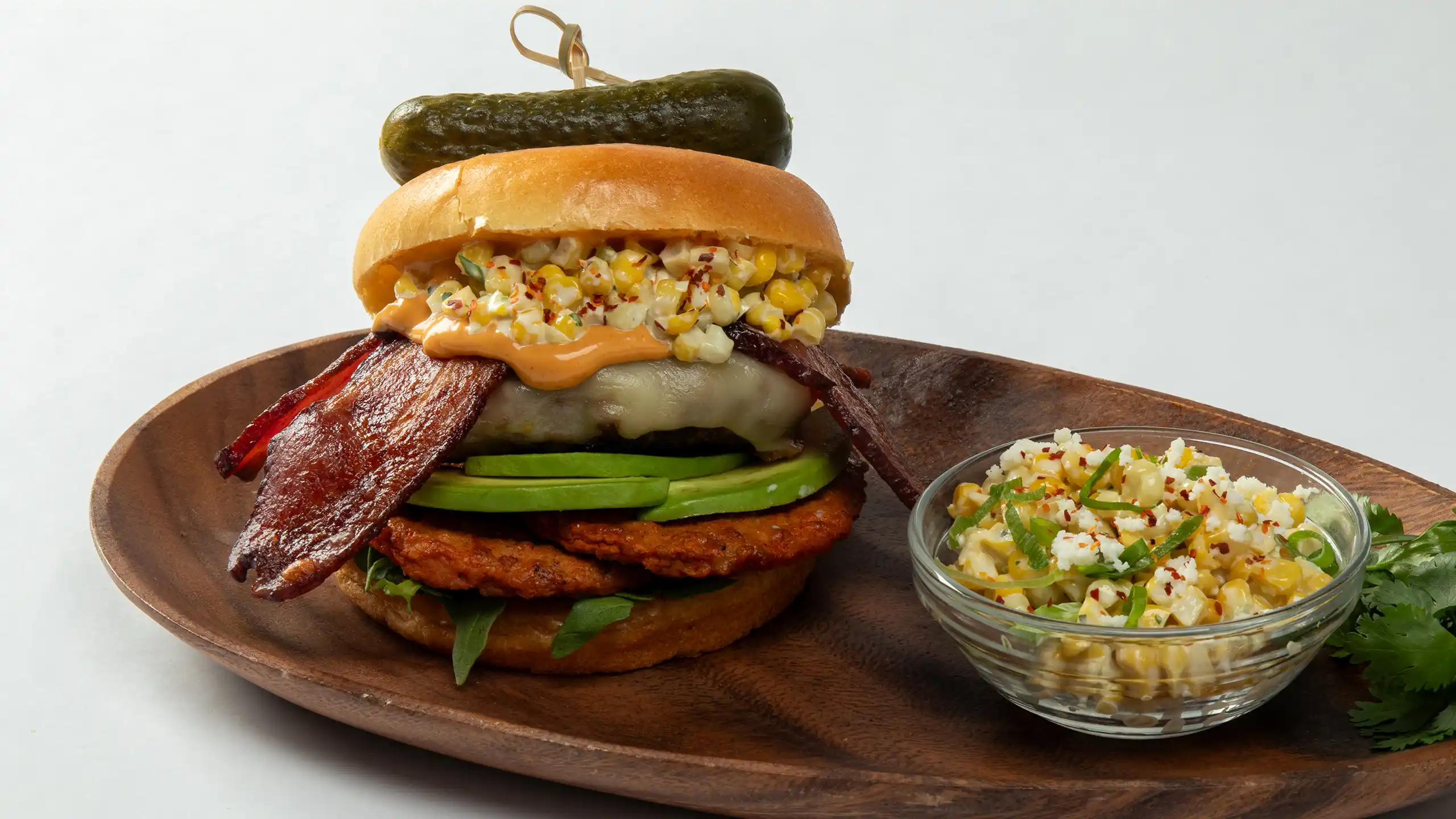 Jones Dairy Farm chicken chorizo patty and dry aged bacon burger with Certified Angus Beef, pepper jack, avocado, elote, and chipotle mayo on a brioche bun