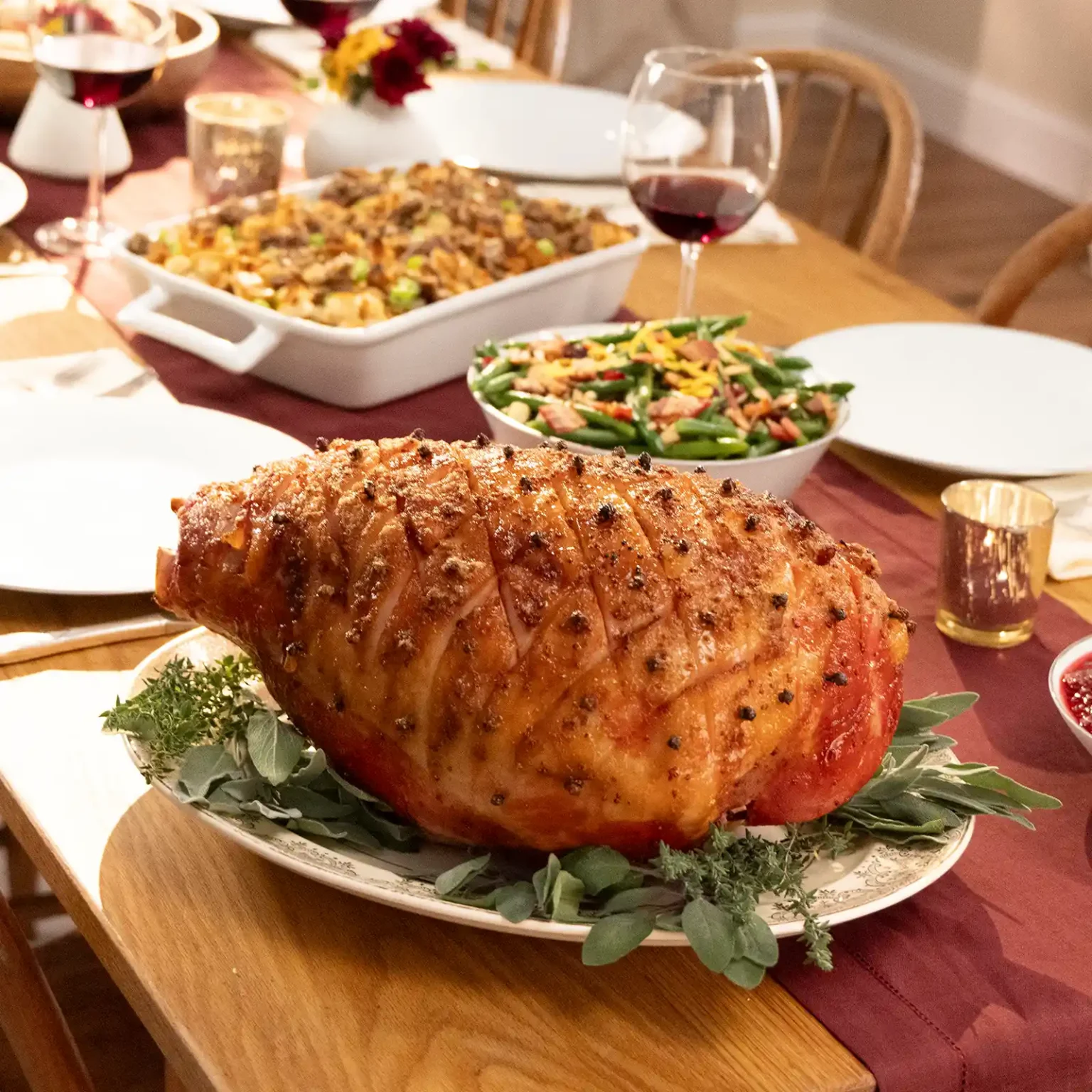Jones Dairy Farm whole glazed Christmas ham with cloves on a holiday dinner table with stuffing and green bean salad