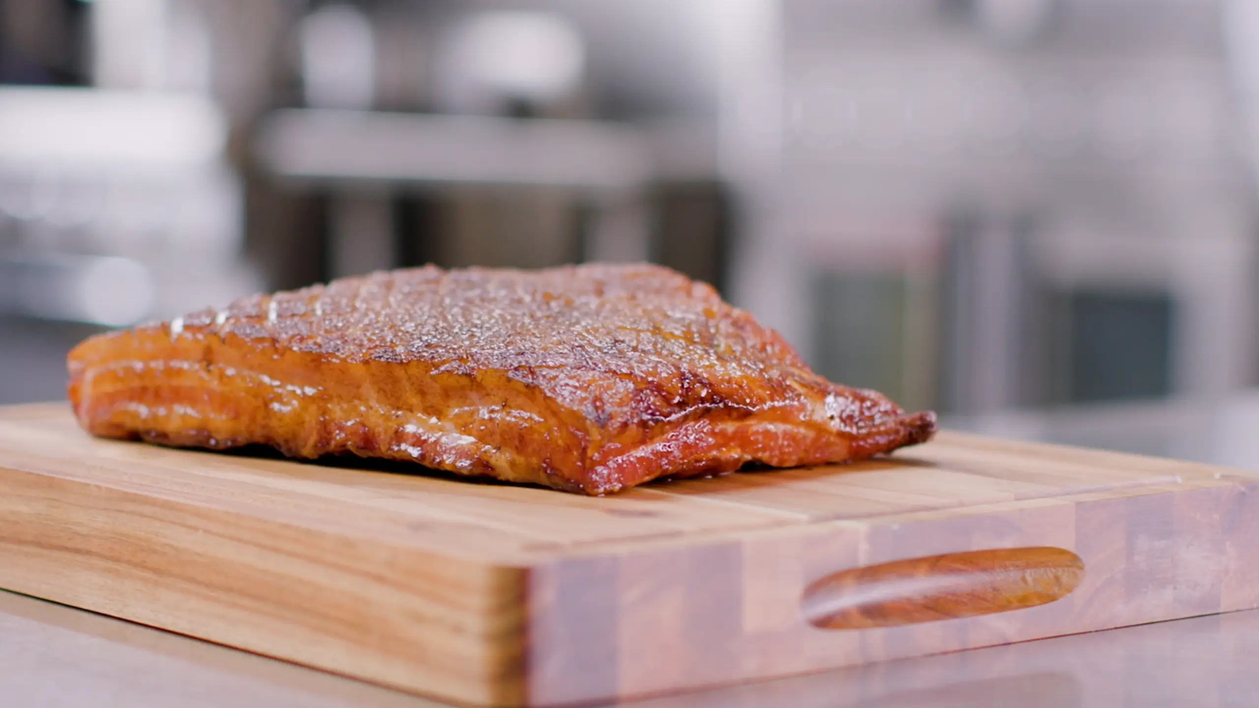 Jones Dairy Farm dry aged cherrywood smoked bacon slab on a cutting board in a commercial kitchen