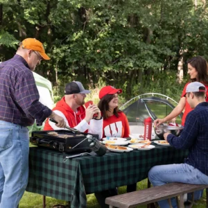 The Jones family gathered around a campsite picnic table with Philip, Ashley, Will Jones, Jordan and Lisa Caras, and their children