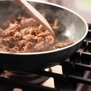 Jones Dairy Farm all natural pork sausage roll browning in a skillet on a gas stovetop