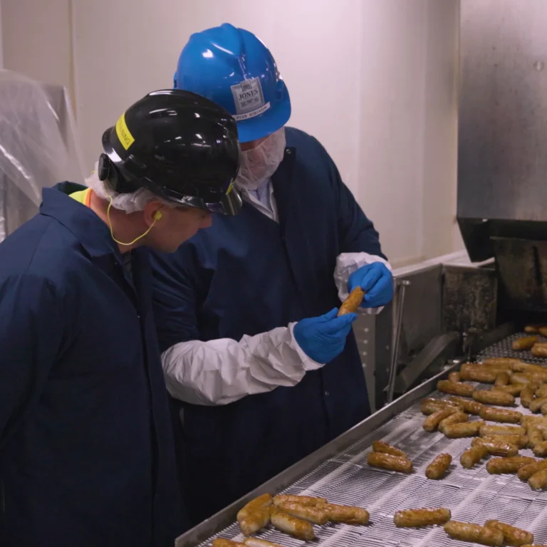 Jones Dairy Farm employees inspecting sausage links on a production line at the manufacturing facility