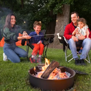Lisa and Jordan Caras roast marshmallows with their two children around a backyard fire pit at dusk
