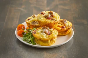 Baked egg muffins with sausage, roasted red pepper, and crumbled cheese, garnished with microgreens