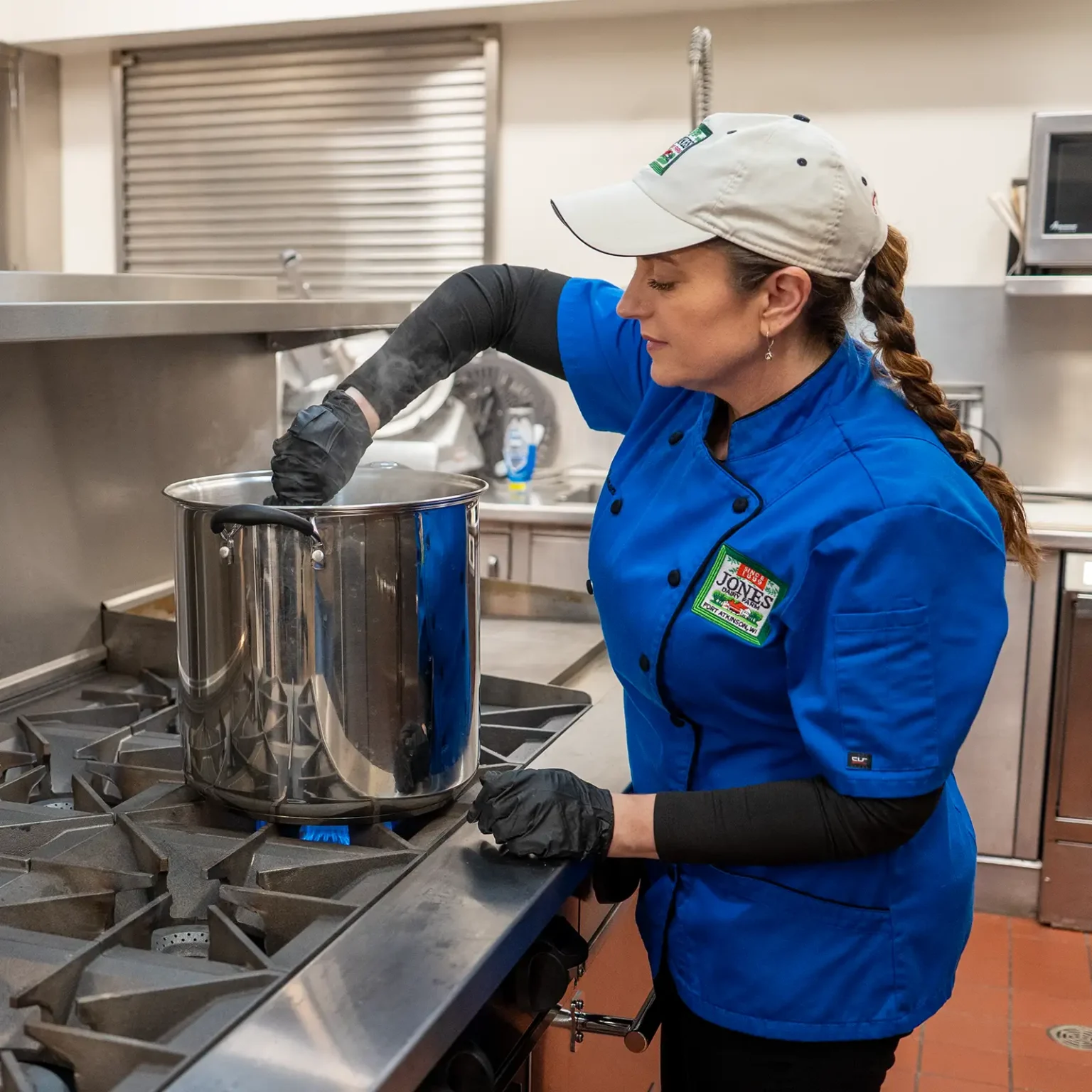 2:02 PMClaude responded: Chef Kate Konen stirs a large stockpot on a gas range in a commercial kitchen, wearing a blue Jones Dairy Farm chef's coat, black gloves, and a white capChef Kate Konen stirs a large stockpot on a gas range in a commercial kitchen, wearing a blue Jones Dairy Farm chef's coat, black gloves, and a white cap