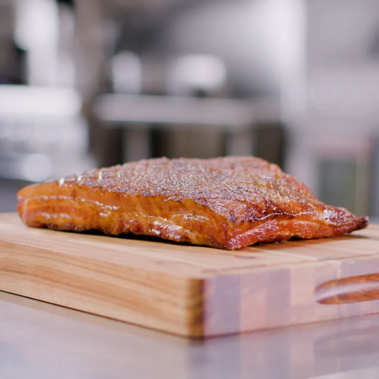 Jones Dairy Farm Cherrywood Smoked Slab Bacon on a wooden cutting board in a commercial kitchen