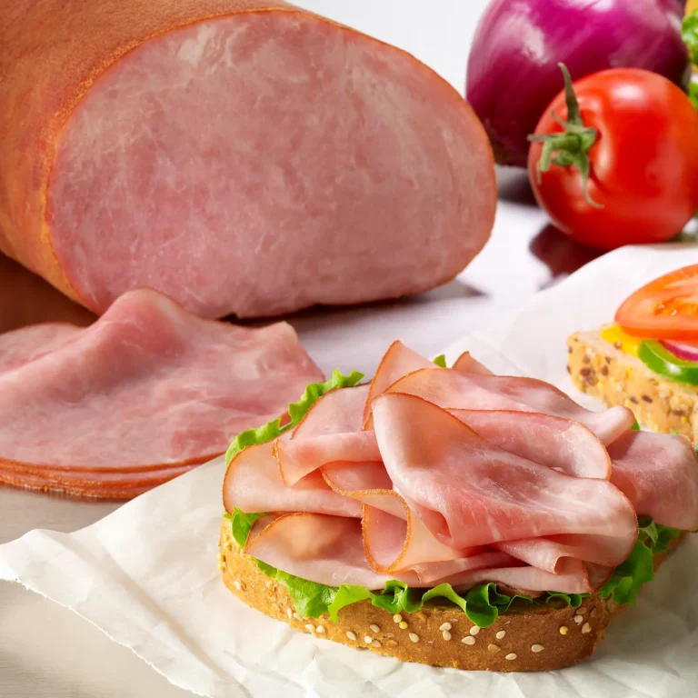 Jones Country Club Boneless Slicing Ham with thinly sliced ham layered on a sandwich with lettuce, sesame seed bread, and fresh tomatoes and red onion
