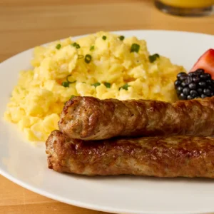 Jones Dairy Farm All Natural pork sausage links served with scrambled eggs and fresh berries on a white plate