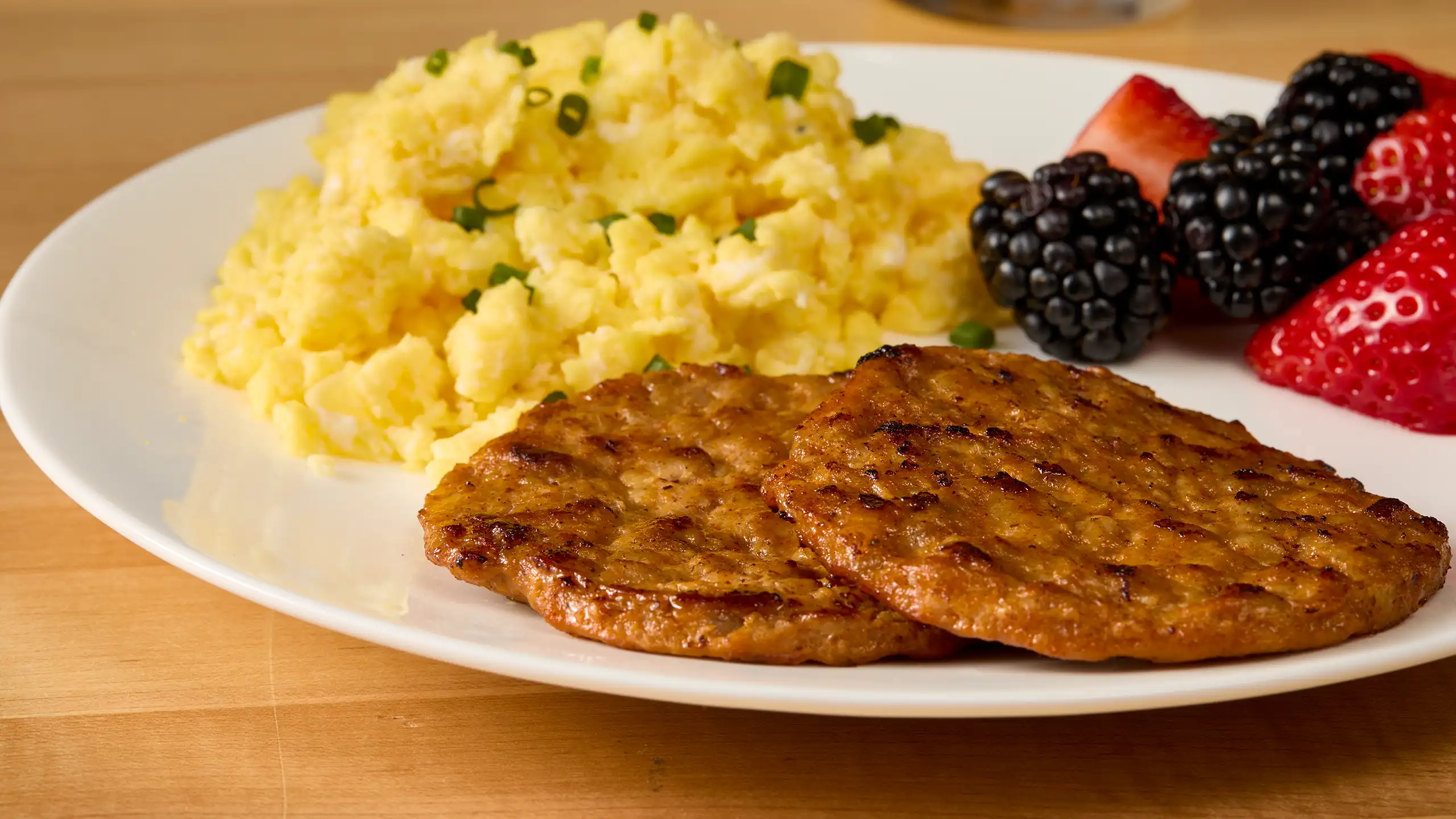 Jones Dairy Farm Gluten Free pork chorizo sausage patties served with scrambled eggs and fresh berries on a white plate