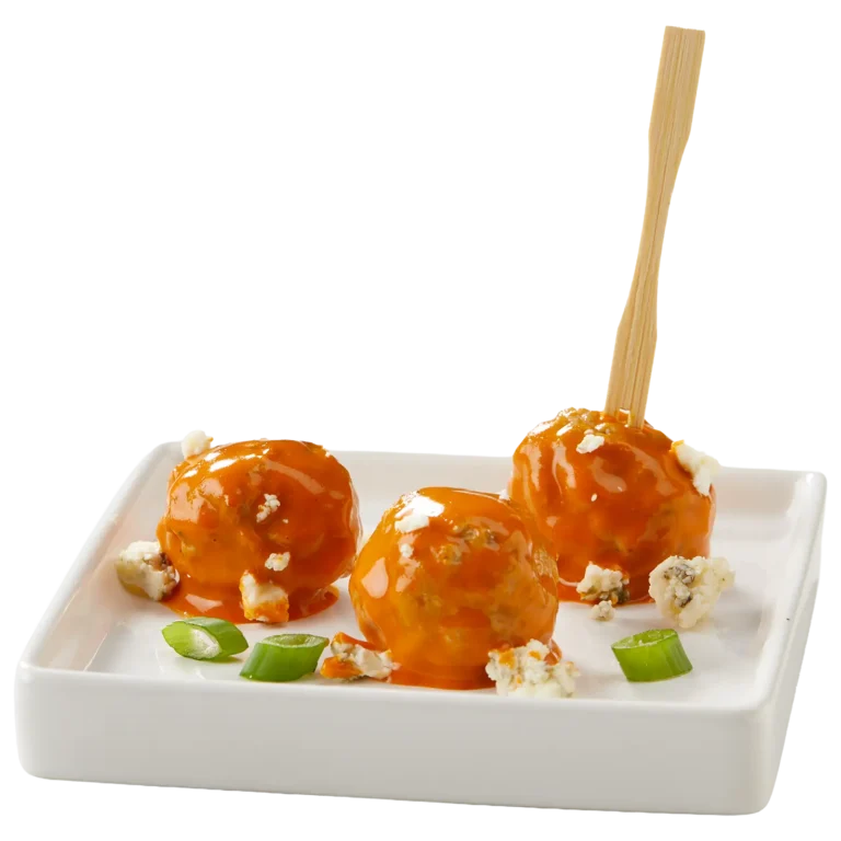 Jones Dairy Farm fully cooked meatballs tossed in buffalo sauce, garnished with blue cheese crumbles and sliced green onions, served on a white plate with a bamboo pick.