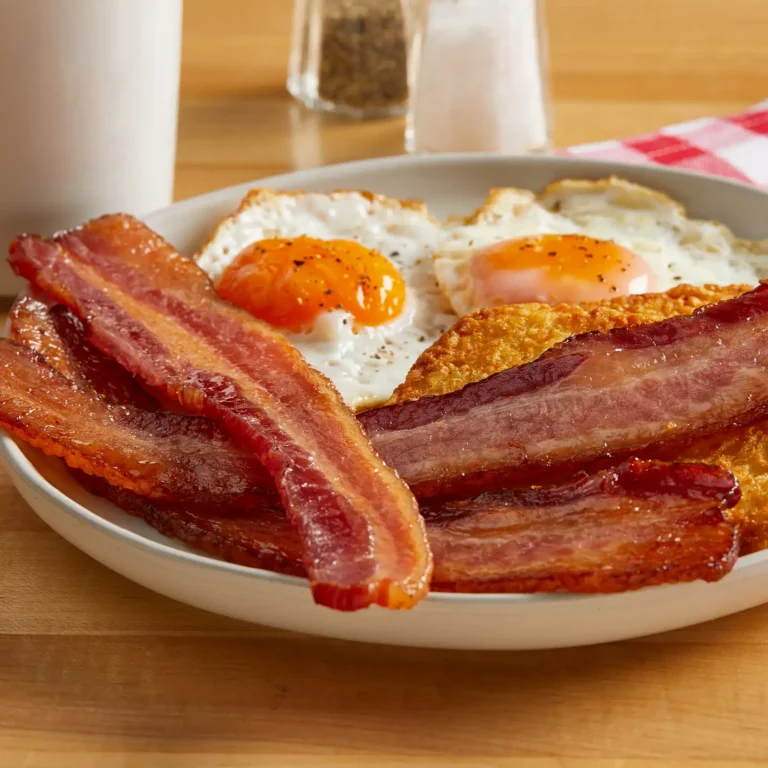 Jones Dairy Farm thick cut hickory smoked bacon strips served with two sunny-side up eggs on a diner-style plate.