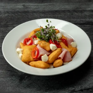 Jones Deli Sliced Ham with golden fried gnocco fritto, fresh mozzarella pearls, sliced sweet red peppers, and microgreens in a white bowl