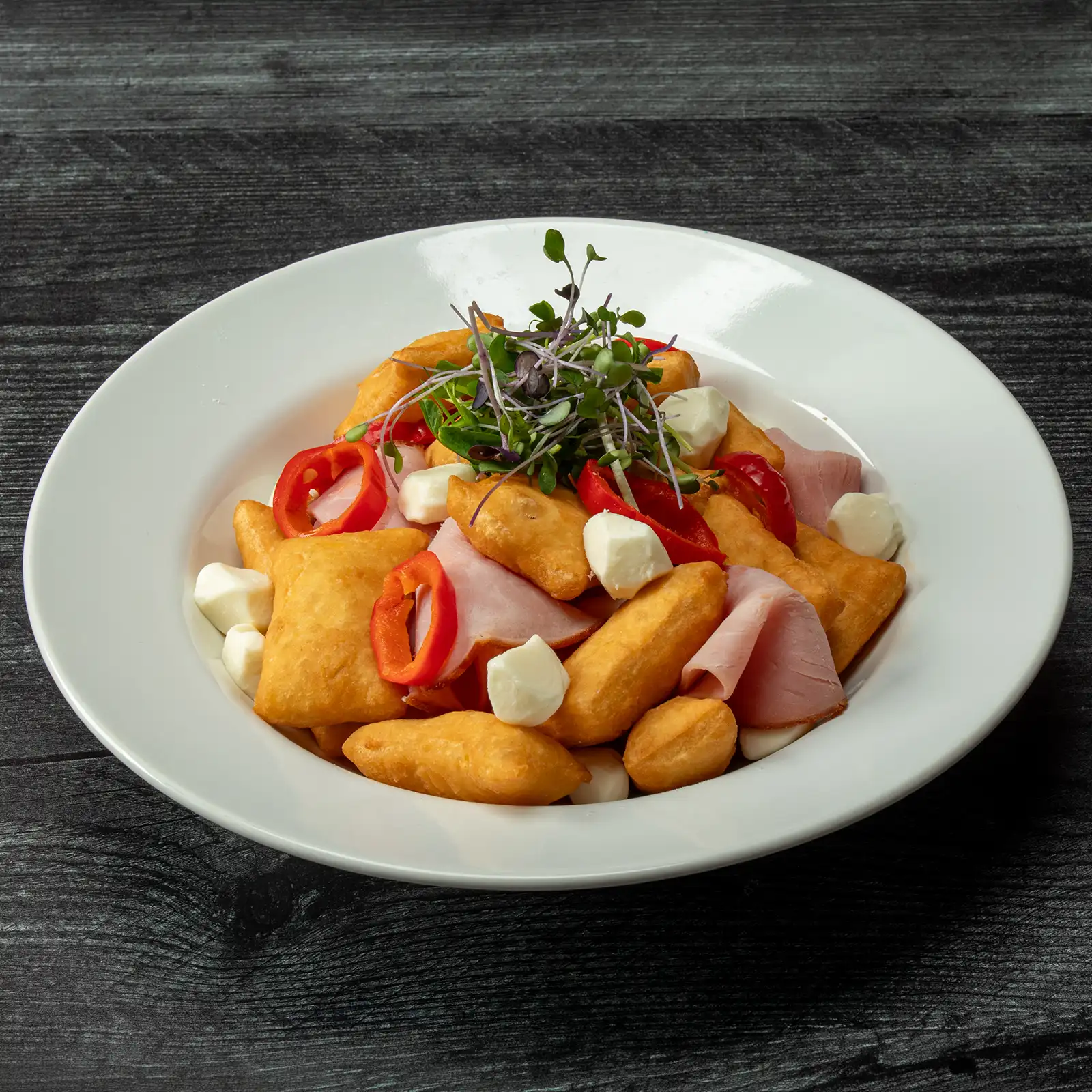 Jones Deli Sliced Ham with golden fried gnocco fritto, fresh mozzarella pearls, sliced sweet red peppers, and microgreens in a white bowl