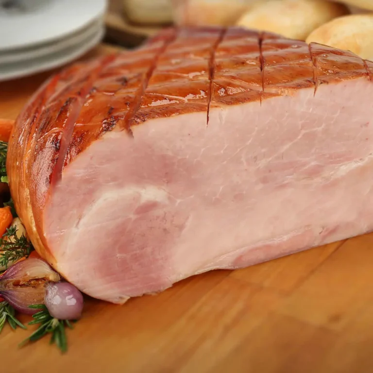 Jones Half Boneless Glazing Ham with cherrywood-smoked glazed exterior and scored diamond pattern, served on a wood carving board with roasted vegetables and dinner rolls
