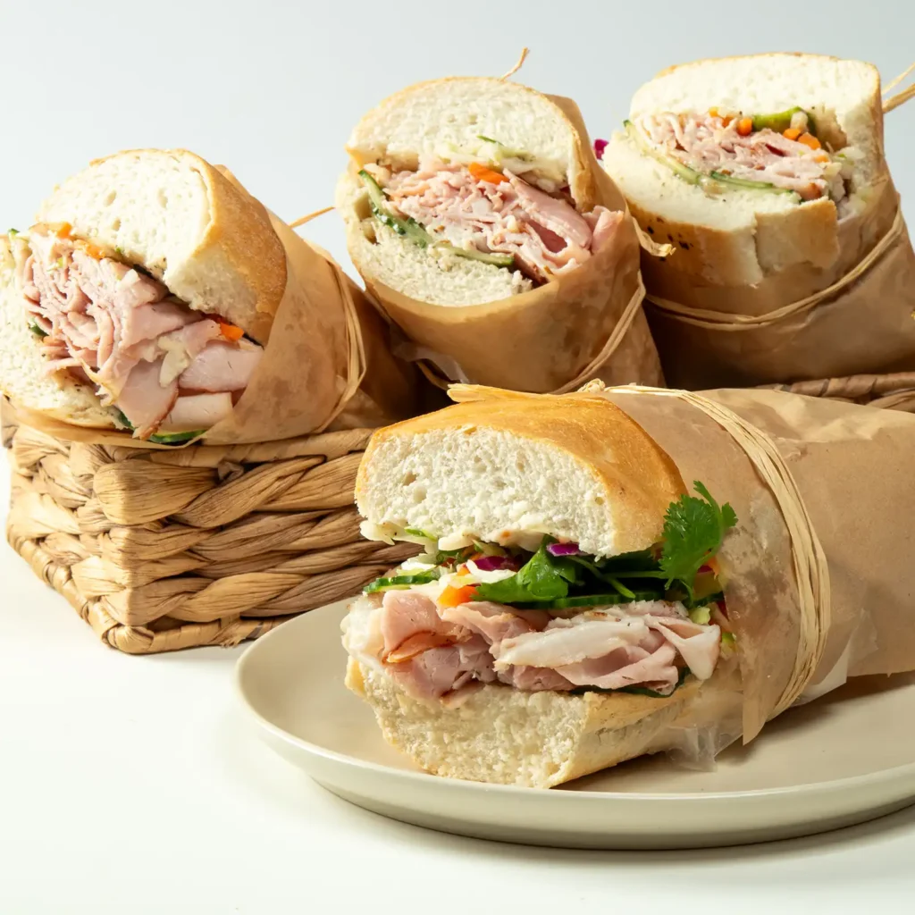 Heritage Ham Banh Mi sandwiches with Jones Heritage Uncured Ham, pickled vegetables, cucumber, and fresh cilantro on baguettes wrapped in brown paper