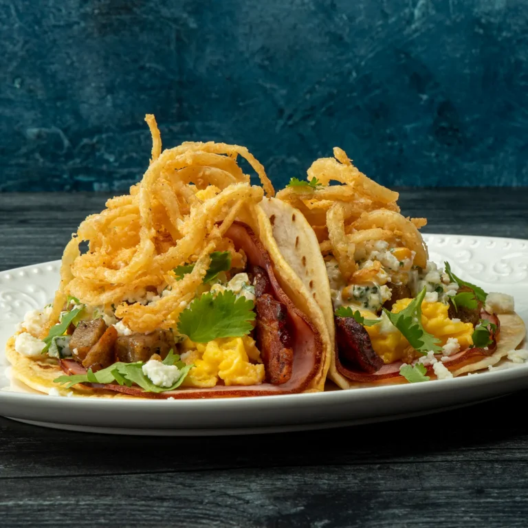 The Hogfather breakfast taco duo with Jones bacon, sausage, and ham, scrambled eggs, crispy onion strings, queso fresco, and fresh cilantro on achiote-dusted flour tortillas