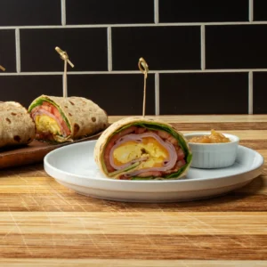 Jones Deli Sliced Ham and scrambled egg lavash breakfast wrap, sliced and plated with a side of onion jam
