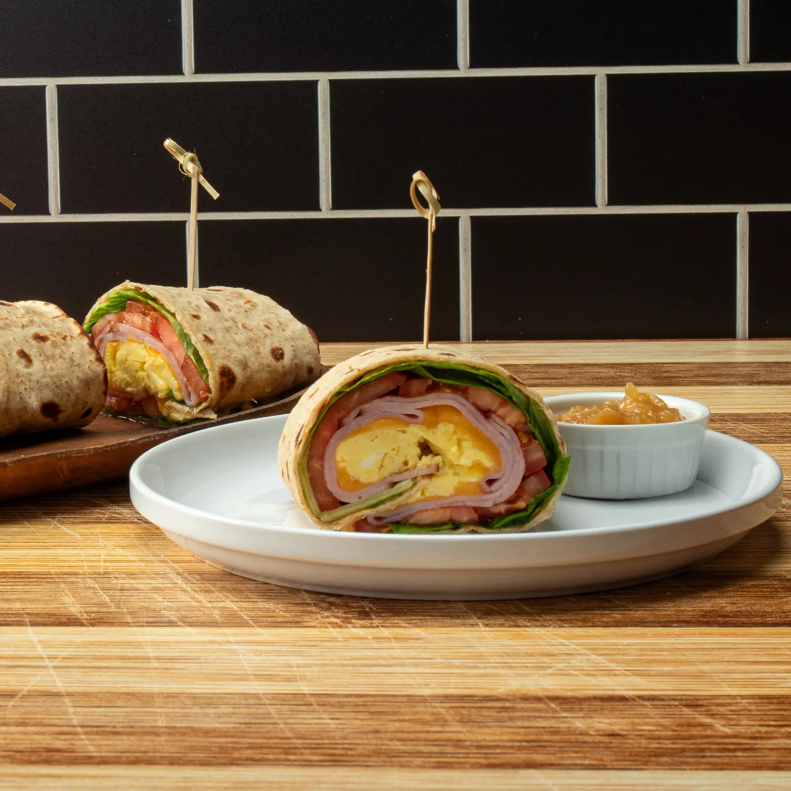 Jones Deli Sliced Ham and scrambled egg lavash breakfast wrap, sliced and plated with a side of onion jam