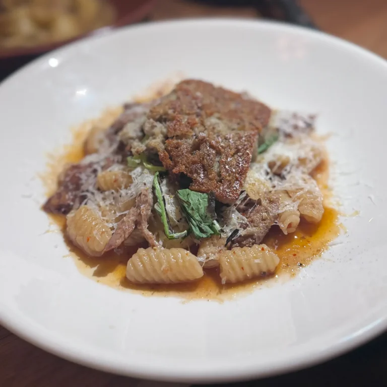 Handmade cavatelli pasta with pistachio basil pesto, shaved parmesan, and a pan-seared slice of Jones Scrapple at House of the Little Pig in Boise, Idaho