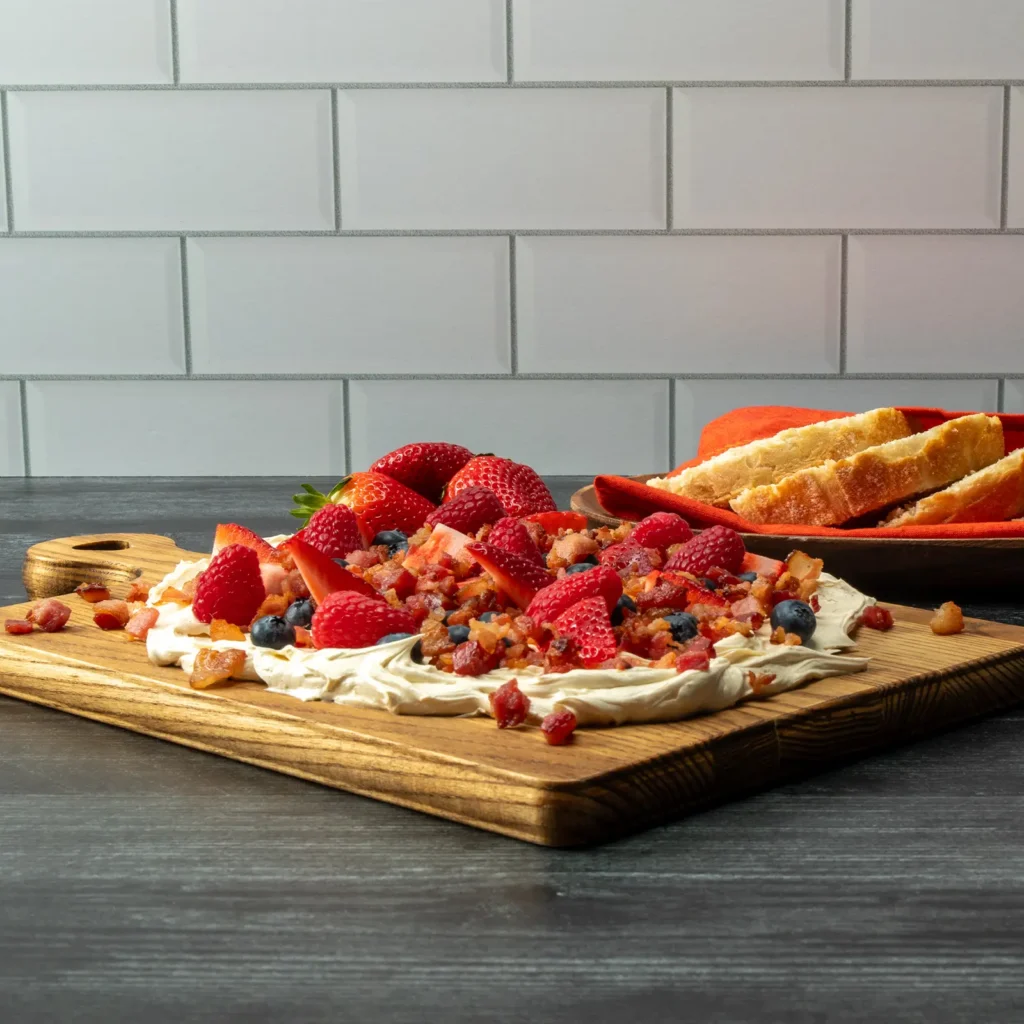 Sunrise Butter Board featuring whipped maple cinnamon butter, fresh strawberries, blueberries, raspberries, and crispy Jones Raw Diced Bacon, served with sliced bread