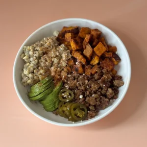 Street corn and sweet potato bowls with Jones sausage, topped with avocado, pickled jalapeños, and cotija cheese