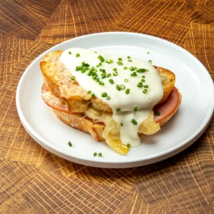 Croque monsieur with Jones Canadian Bacon, gruyere cheese, and béchamel sauce on griddled French bread, topped with fresh chives