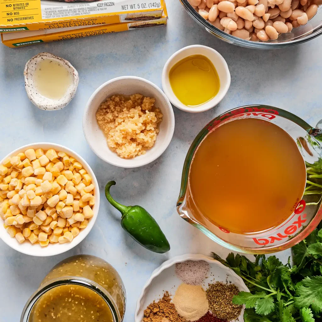 Ingredients for creamy white chicken sausage chili, including a box of Jones Golden Brown Chicken Sausage, white beans, corn, salsa verde, chicken broth, garlic, jalapeño, cilantro, lime, and spices.