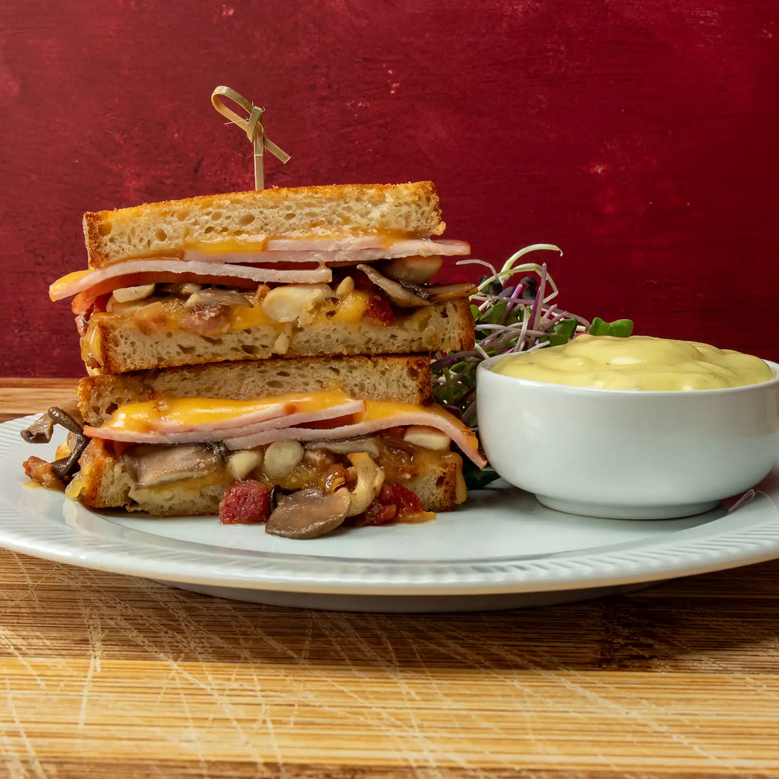 Double Bacon Mushroom Melt sandwich with Jones Canadian bacon, smoked gouda, sautéed mushrooms, and bacon onion jam, served with béarnaise sauce