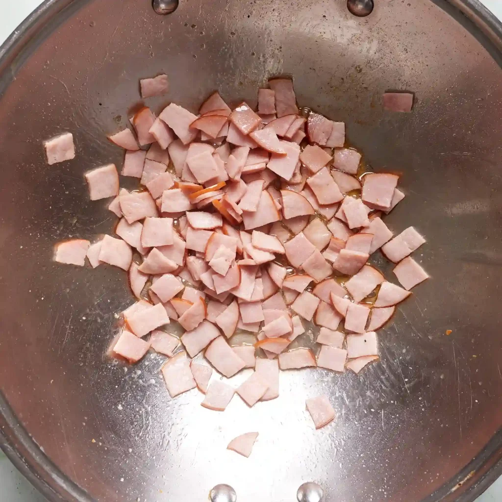 Diced Jones Canadian bacon cooking in a wok, the first step in making kimchi fried rice.