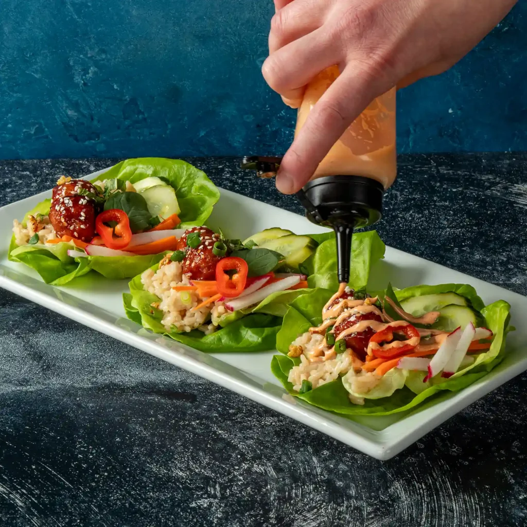 Jones Pork and Bacon Meatballs in Korean BBQ sauce served in Bibb lettuce cups with sushi rice, herbs, and quick pickle vegetables