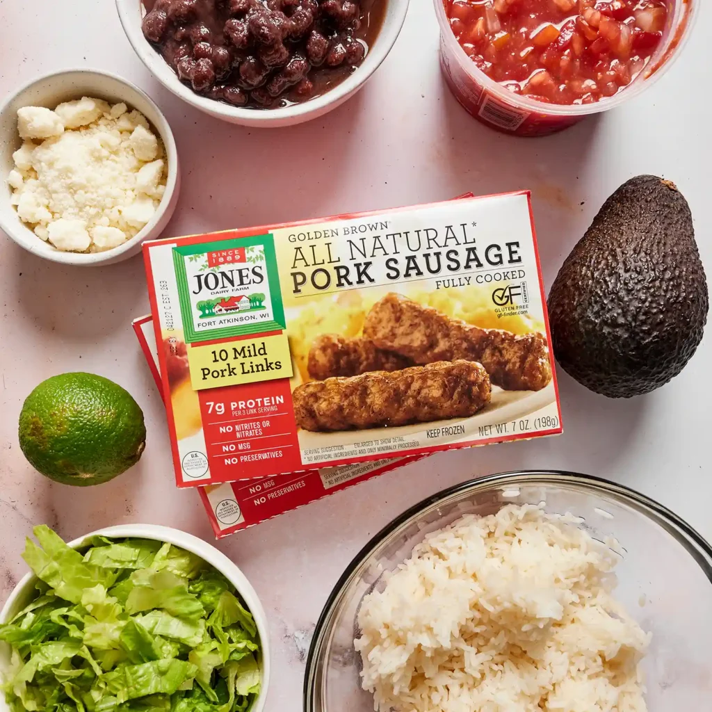 Ingredients for a taco rice bowl, including a box of Jones All Natural Pork Sausage, black beans, pico de gallo, cotija cheese, avocado, lime, shredded lettuce, and rice.