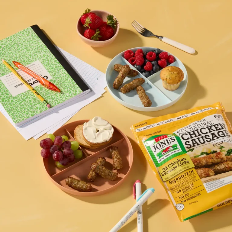 Jones Dairy Farm chicken sausage links served alongside a bagel, fresh fruit, and a muffin on a back-to-school themed table with a notebook and pencils.