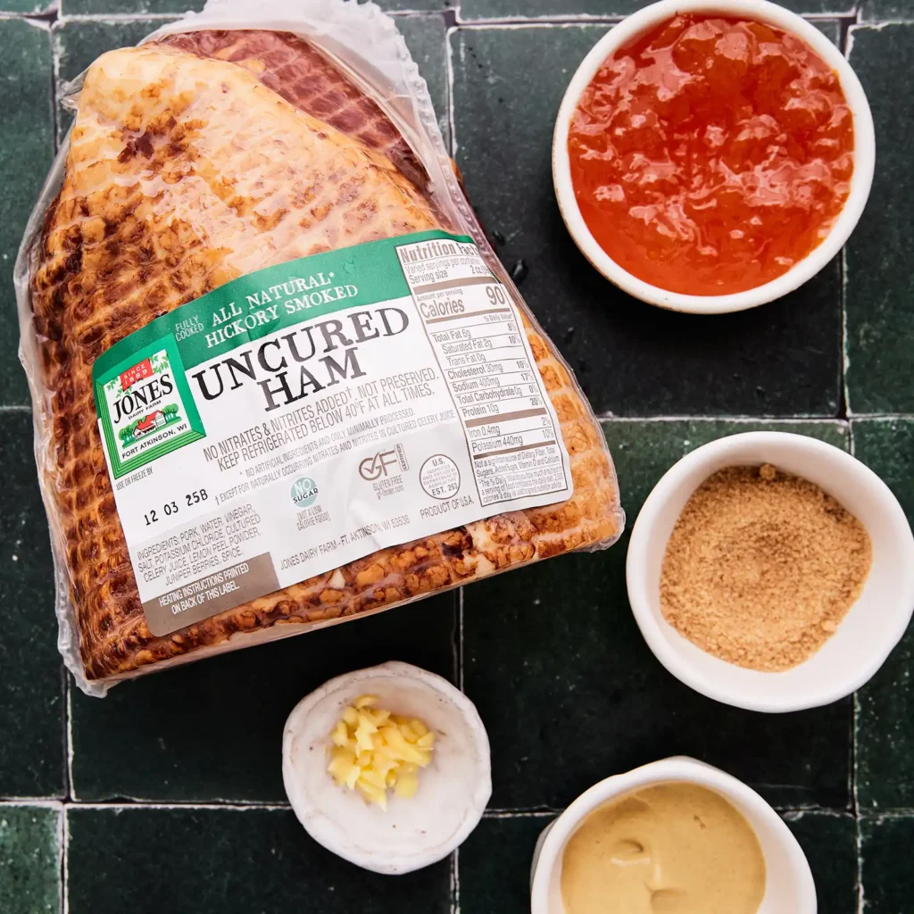 Ingredients for apricot Dijon glazed ham, including a package of Jones Uncured Ham, apricot preserves, brown sugar, garlic, and mustard.