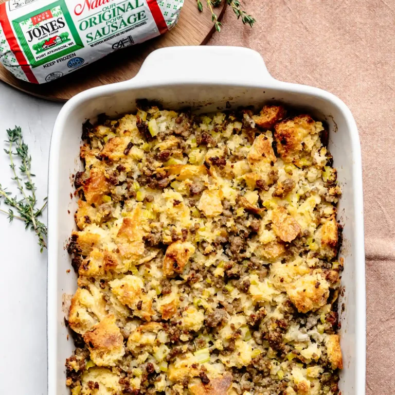 Baked sourdough sausage stuffing in a casserole dish next to a roll of Jones Original Pork Sausage.