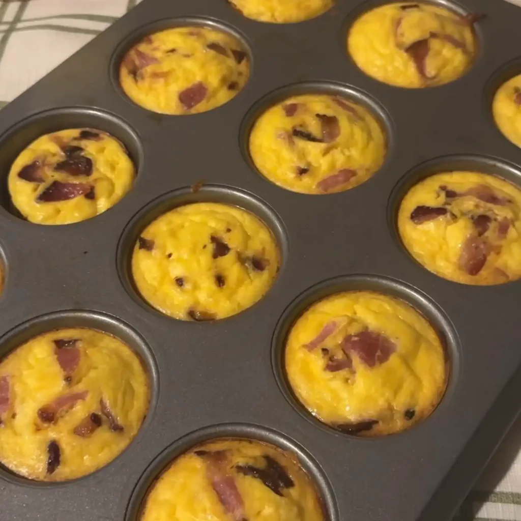 Baked bacon and tater tot egg bites in a muffin tin, golden and set.