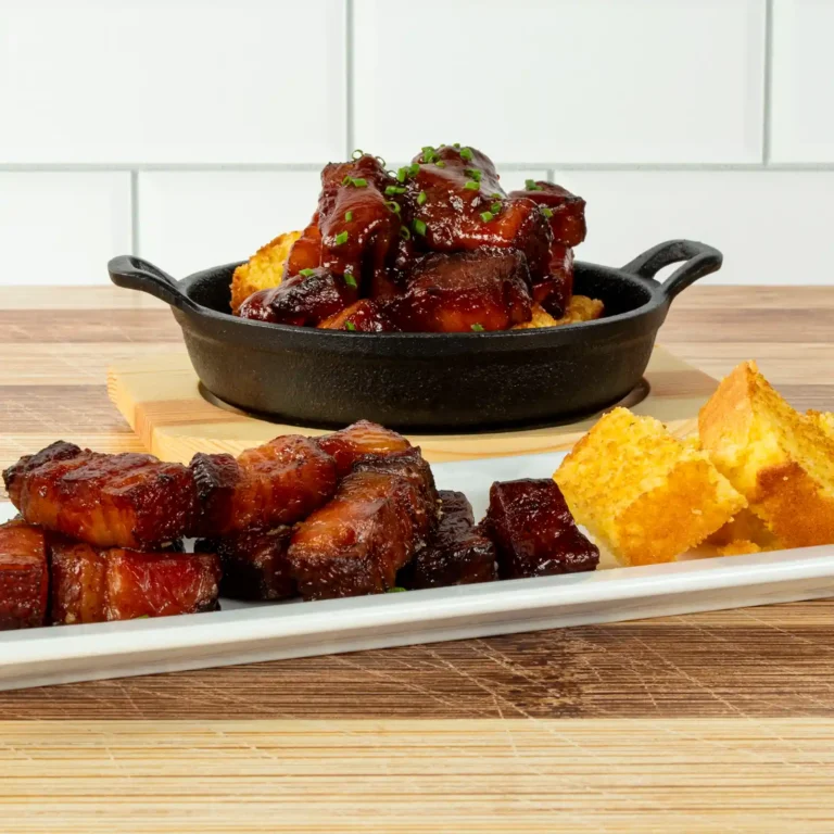 Bacon slab burnt ends served two ways, plated over cornbread cubes and in a cast iron skillet with barbecue glaze